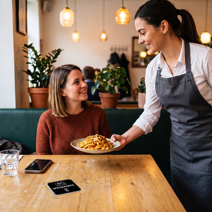 Bedienung serviert Pasta, auf dem Tisch liegt die Speisekarten-NFC-Karte | Deutsch