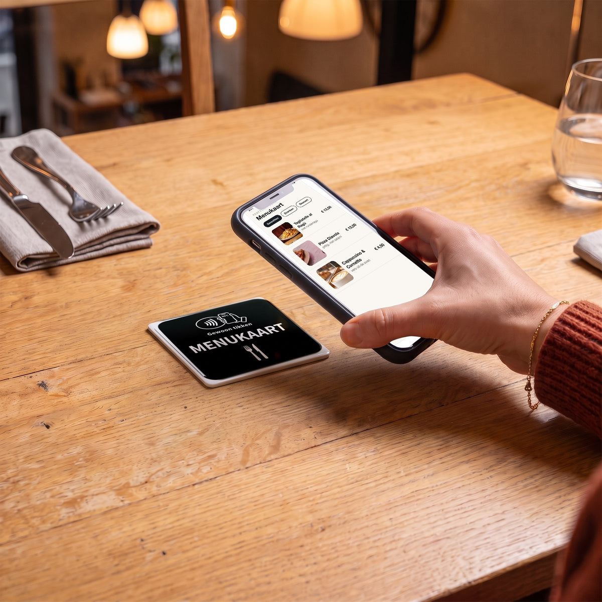 Handy wird an die Speisekarten-NFC-Karte gehalten, auf dem Bildschirm öffnet sich die Speisekarte | Nederlands