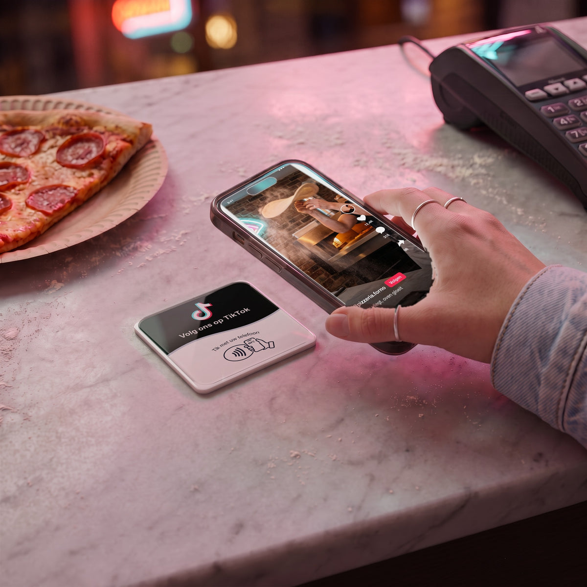 Handy wird an die TikTok-NFC-Karte gehalten, auf dem Bildschirm läuft das Video der Pizzeria | Nederlands