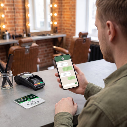 Kunde schreibt am Handy eine Nachricht, die NFC-Karte liegt auf dem Tresen | English